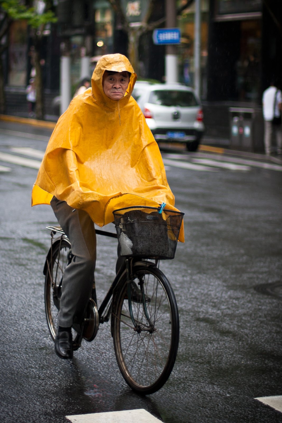 A cyclist wearing a rain poncho in Shanghai, illustrating rain protection.