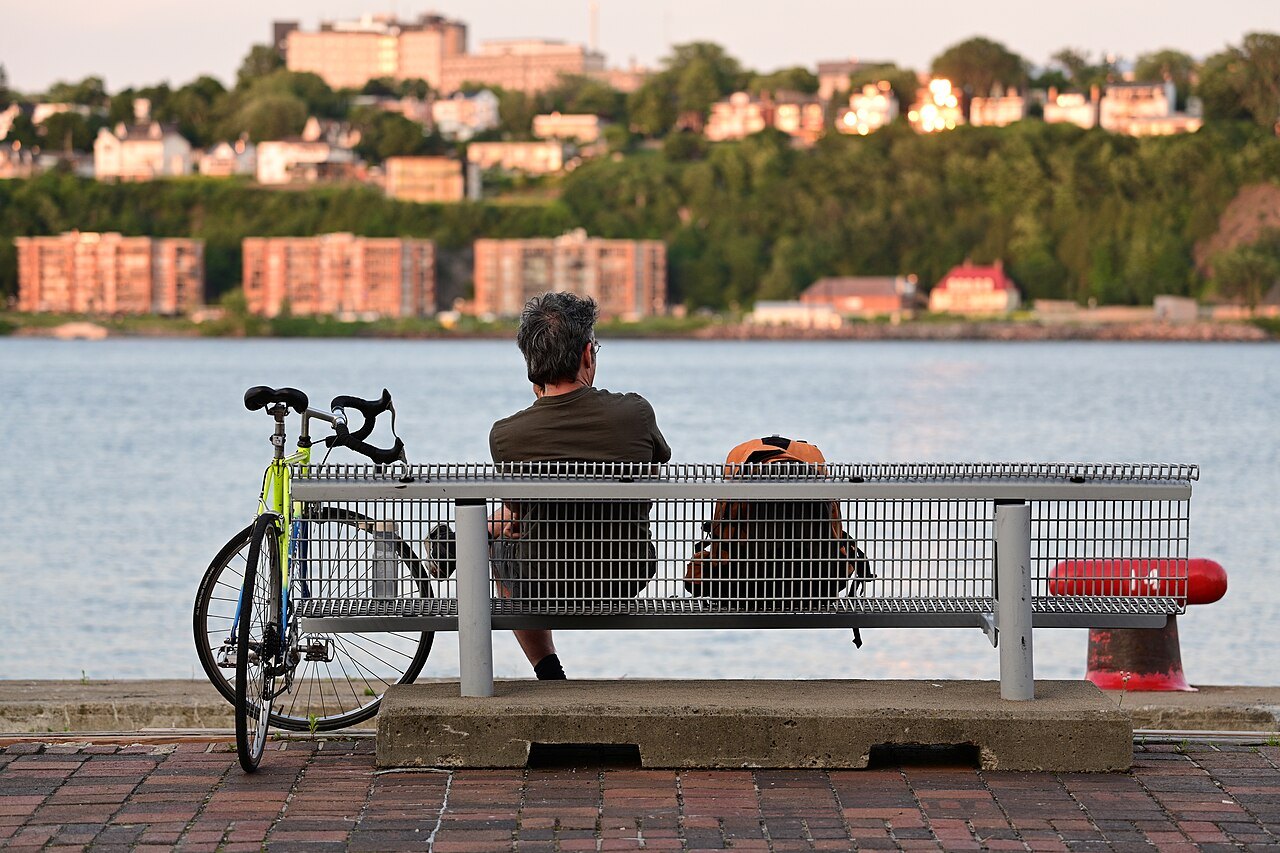 A rest beside a bicycle on a riverside bench in Québec, illustrating a stopping place.