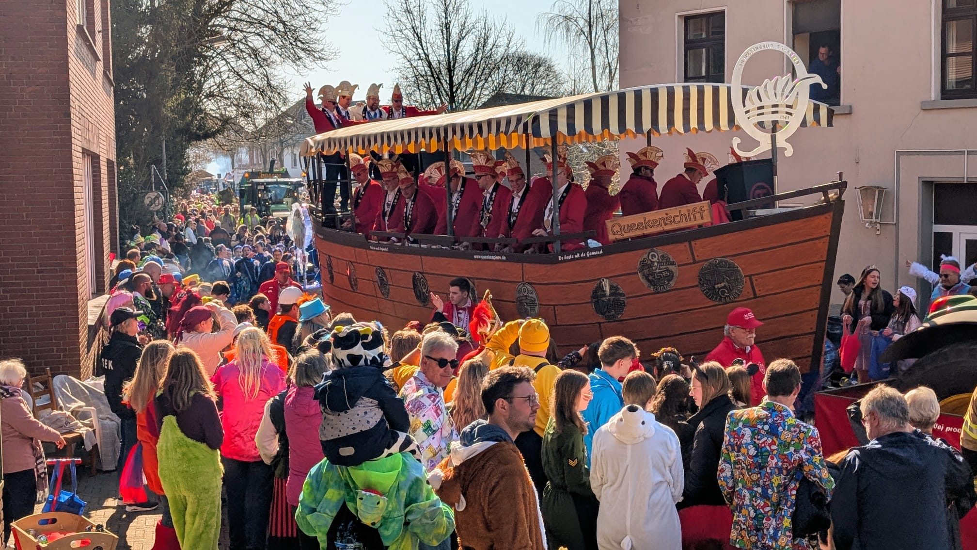 Karnevalszug mit Zuschauern in Kostümen und einen Karnevalswagen